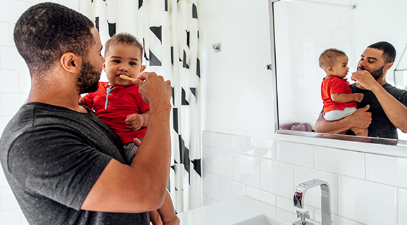 Man brushing babys teeth